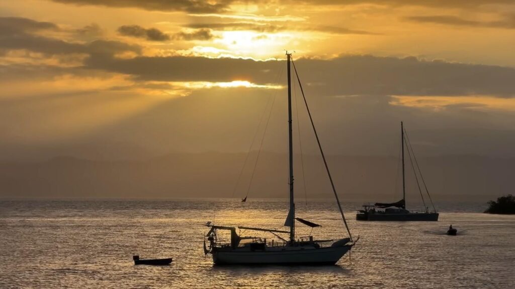 Sailboats anchored on calm water during sunset near a floating bar in Bocas del Toro.